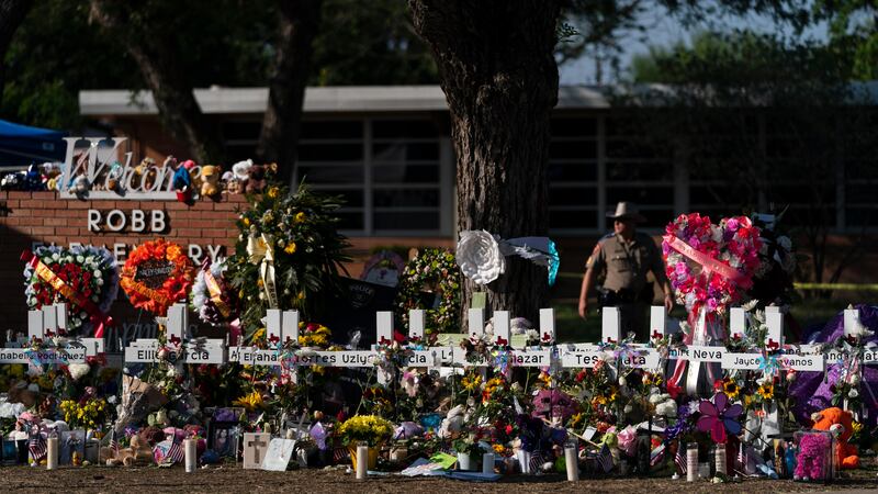 ARCHIVO - Flores y velas se colocan alrededor de cruces el 28 de mayo de 2022, en un monumento...