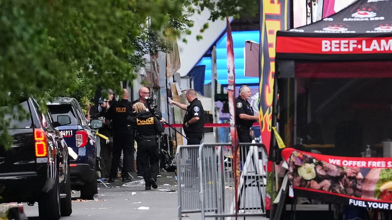 Un fotógrafo de escena de crimen llega mientras las fuerzas de seguridad investigan el lugar...