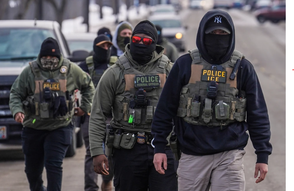 Federal agents walk down a street while conducting immigration enforcement operations in...