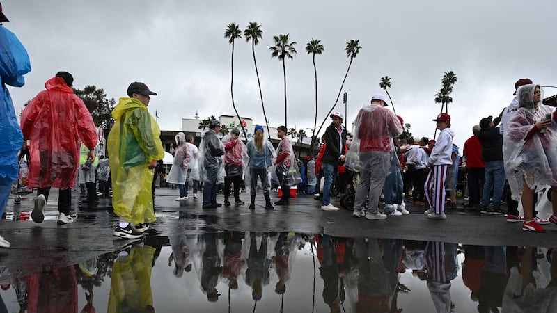 Aficionados reflejados en un charco después de que llovió durante el Desfile de las Rosas...