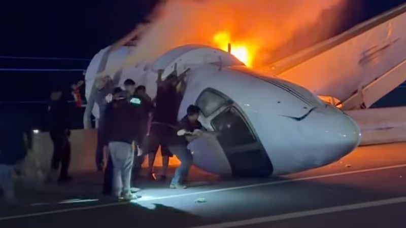 People attempt to pull passengers out of a plane after it crashed on a highway Tuesday, June...
