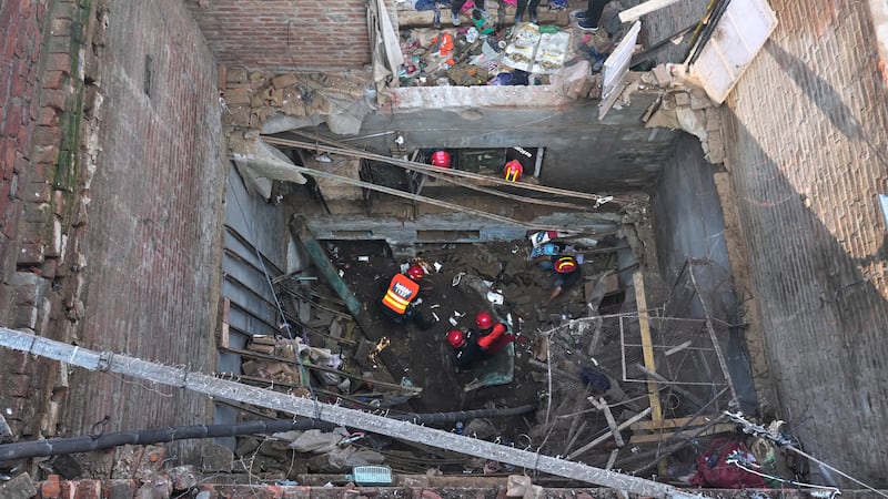 Rescatistas buscan entre los escombros de una casa donde se derrumbó el tejado en Lahore,...