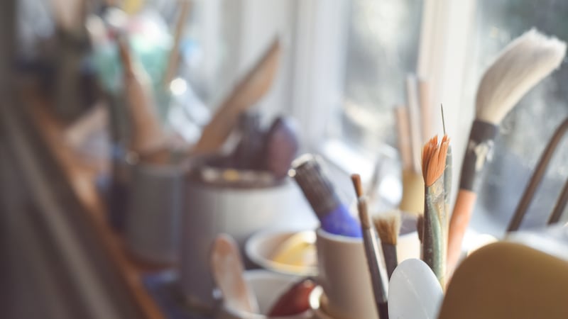 Paint brushes pens pencils and other art tools and equipment in a working art studio