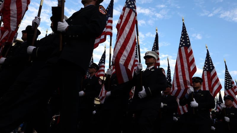 Miembros del Departamento de Bomberos de Nueva York marchan con banderas estadounidenses...