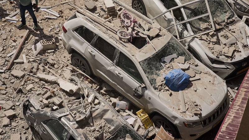 Un hombre inspecciona los daños a autos y un edificio de apartamentos alcanzado por un misil...