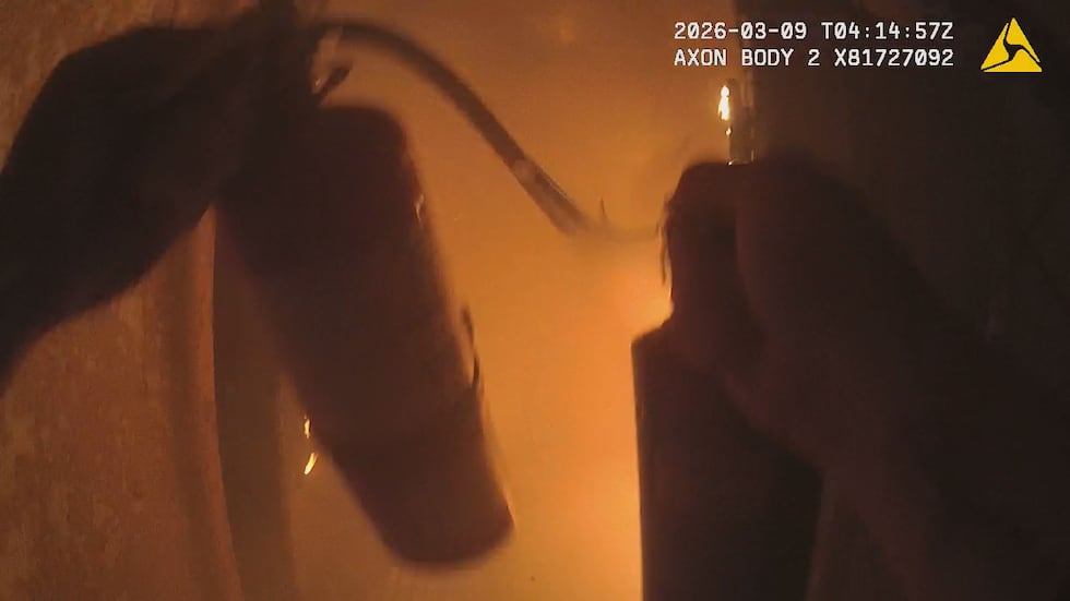 Officer Martin holds two fire extinguishers and attempts to put out the flames.