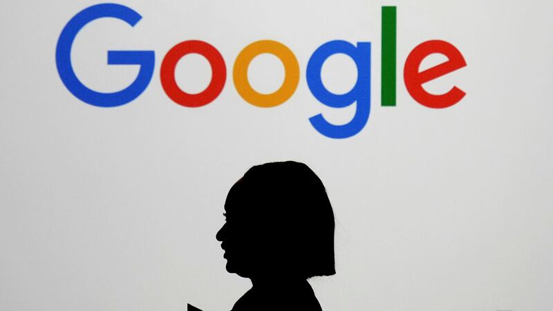 ARCHIVO – Una mujer camina frente a una pantalla gigante con el logotipo de Google en un...